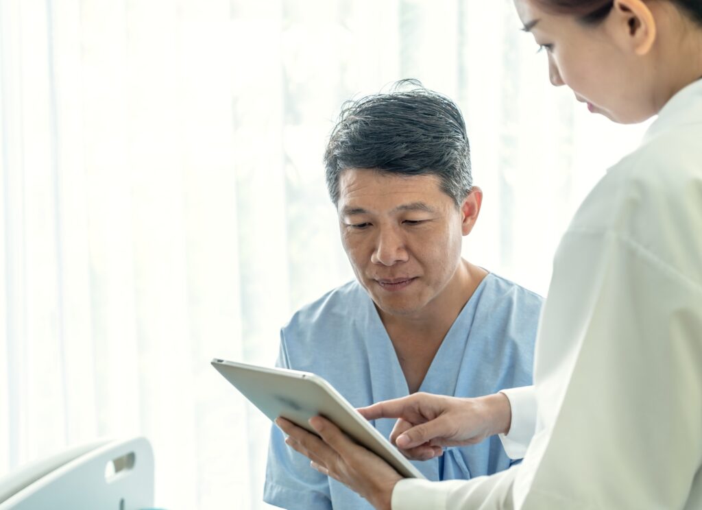 asian senior patient hospital bed discussing with female doctor