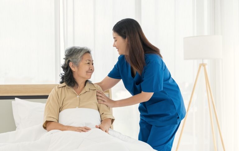 nurse assistant concept woman blue uniform is helping elderly woman bed