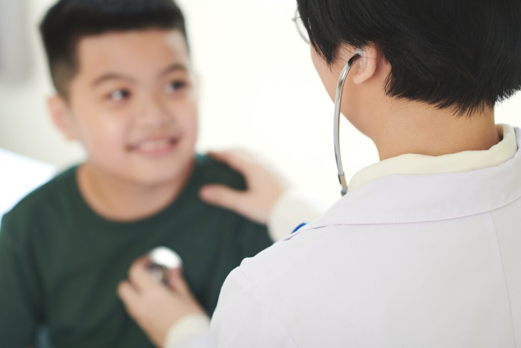 rear view female doctor examining boy with stethoscope medical exam